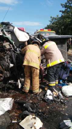El Cuerpo de Bomberos trata de sacar el cadáver del pick-up gris.