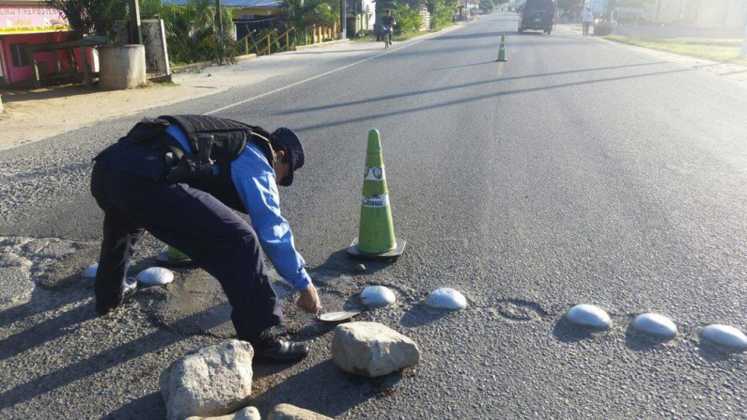 Un agente policial repara baches en Atlántida.