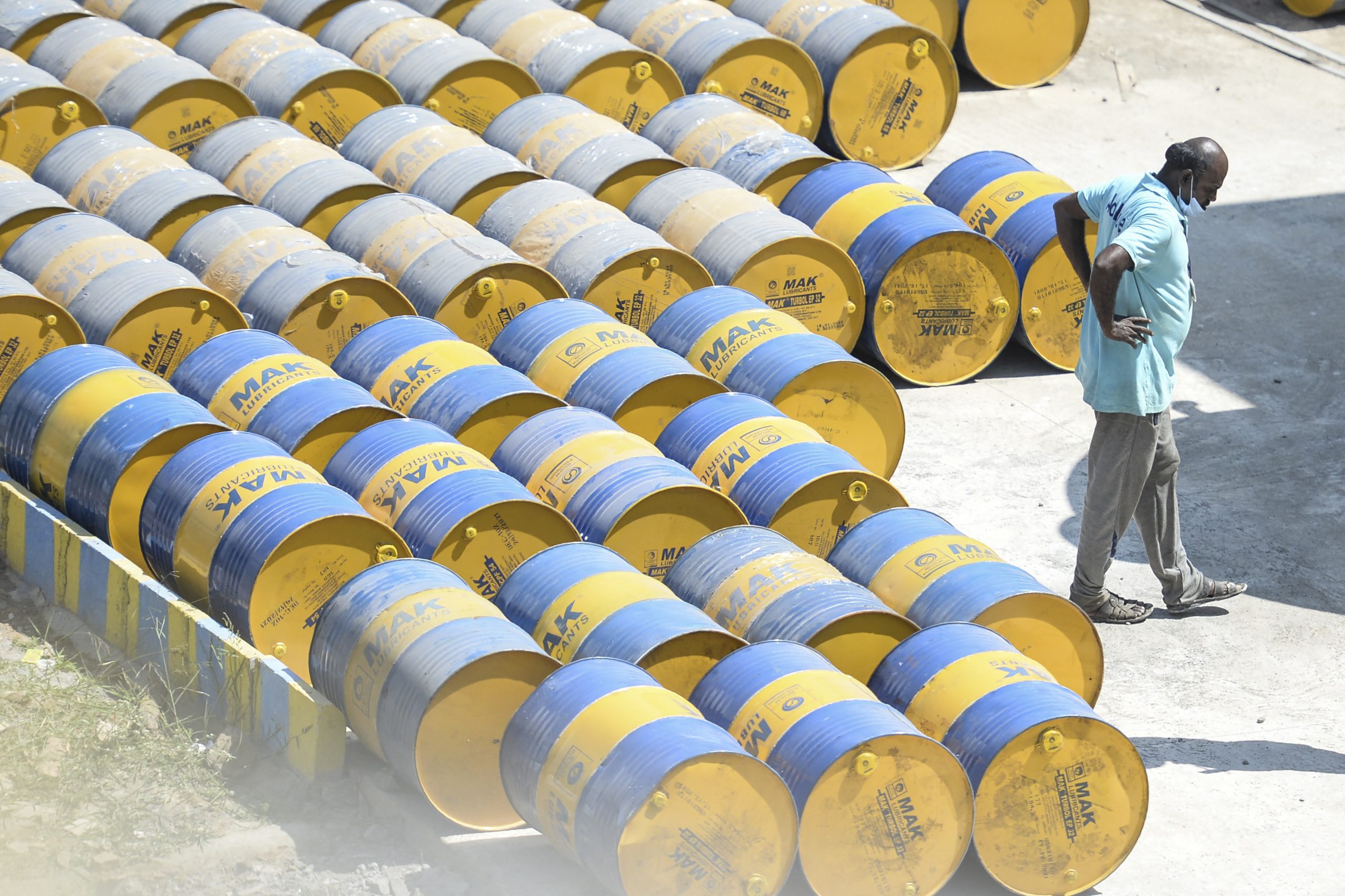 Un trabajador pasa junto a barriles de petróleo en una estación de servicio en Chennai, India.